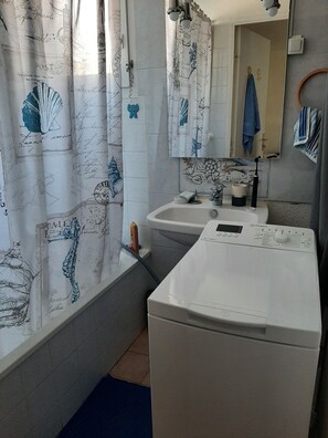 A bathroom with a white sink, a mirror, and a shower curtain with nautical designs. - Marseillan house without opposite in the peace, garden terrace, in a residence (Marseillan)