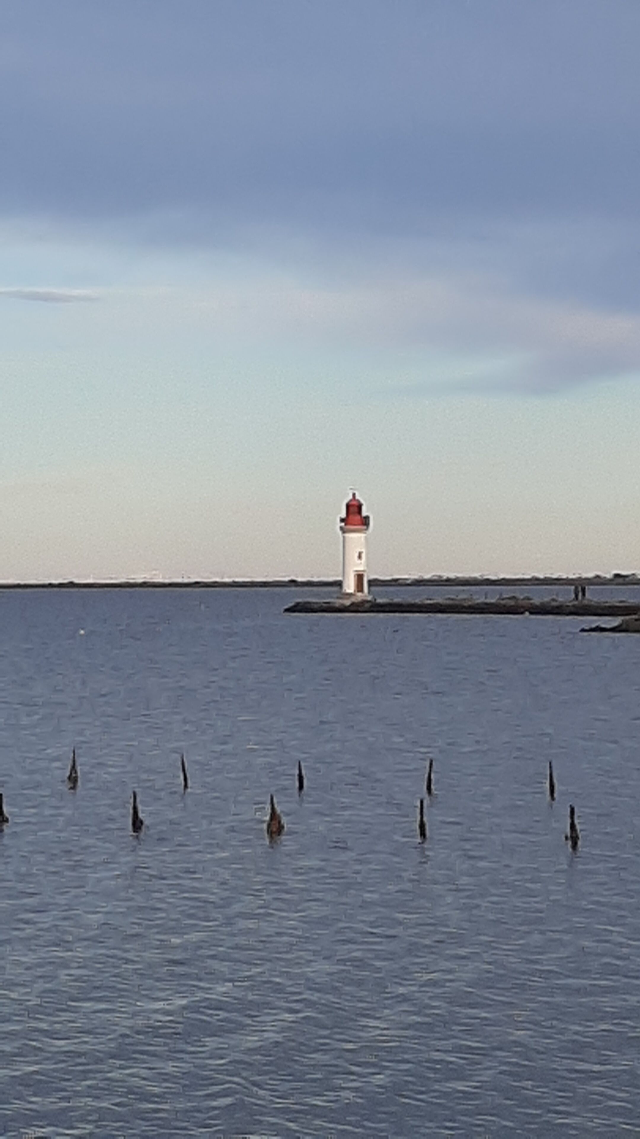 A lighthouse on a small island in the middle of a calm body of water.