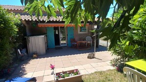A patio with a table and chairs, a covered seating area, and a small garden with flowers. - Marseillan house without opposite in the peace, garden terrace, in a residence (Marseillan)