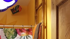 Une salle de bain avec une porte en bois, un rideau de douche orné de motifs de cactus et un porte-serviettes avec une serviette.