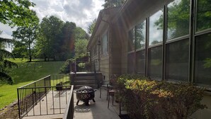 A covered outdoor area with a fire pit, a chair, and a small table.