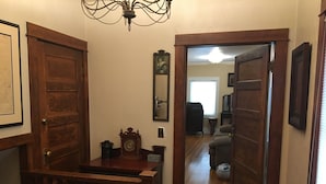 A hallway with wooden doors, a clock, and a mirror on the wall. - Historic Downtown Carriage House (Flagstaff)
