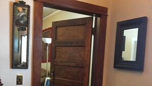 A wooden door with a mirror on the wall, a small table, and a lamp. - Historic Downtown Carriage House (Flagstaff)