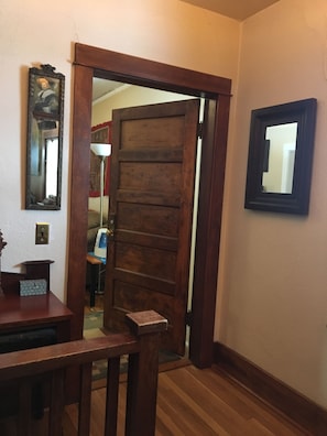 Une porte en bois avec un miroir sur le mur, une petite table et une lampe.
