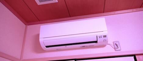 A white air conditioning unit mounted on a wall with a power outlet nearby.