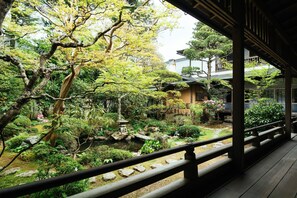 A traditional Japanese garden with a wooden deck, stone lantern, and various plants. - Koyasan Syukubo Zofukuin (Koya)