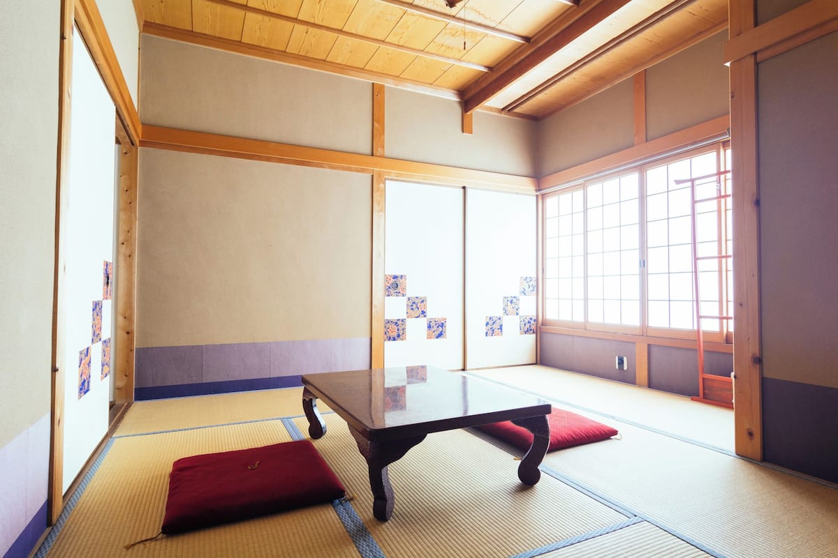 Une pièce avec un sol recouvert de tatamis, une petite table basse et des coussins.