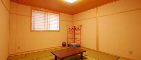 A traditional Japanese room with tatami flooring, a low wooden table, a window with shoji screens, and a red folding screen.