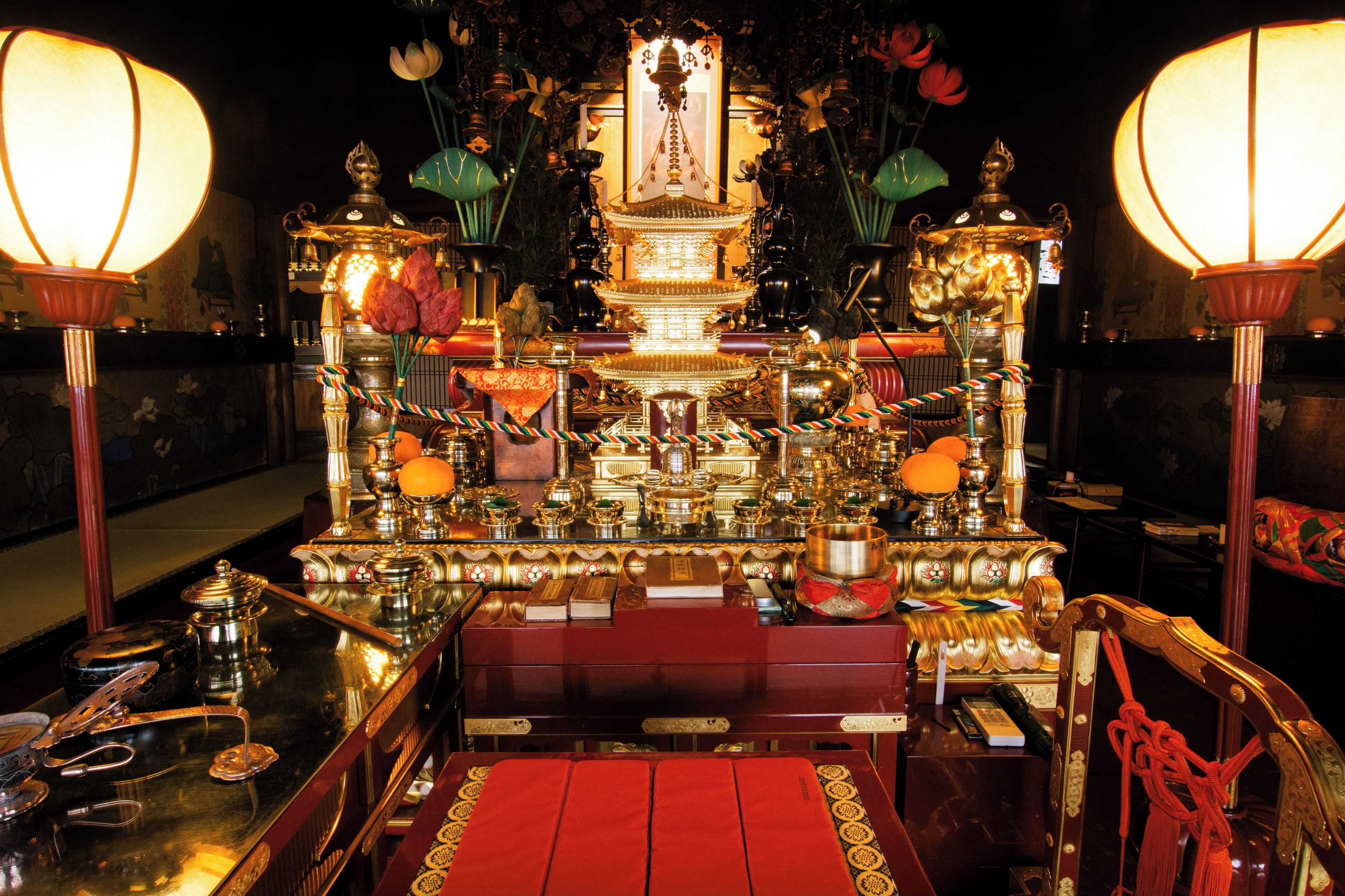Ein traditioneller Altar mit aufwendiger Dekoration, einer zentralen Figur und zwei großen Lampen.