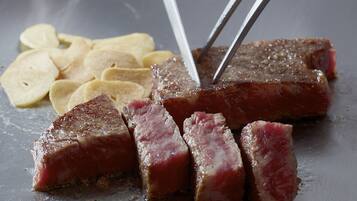 Un bistec con tenedor y cuchillo, acompañado de papas fritas.
