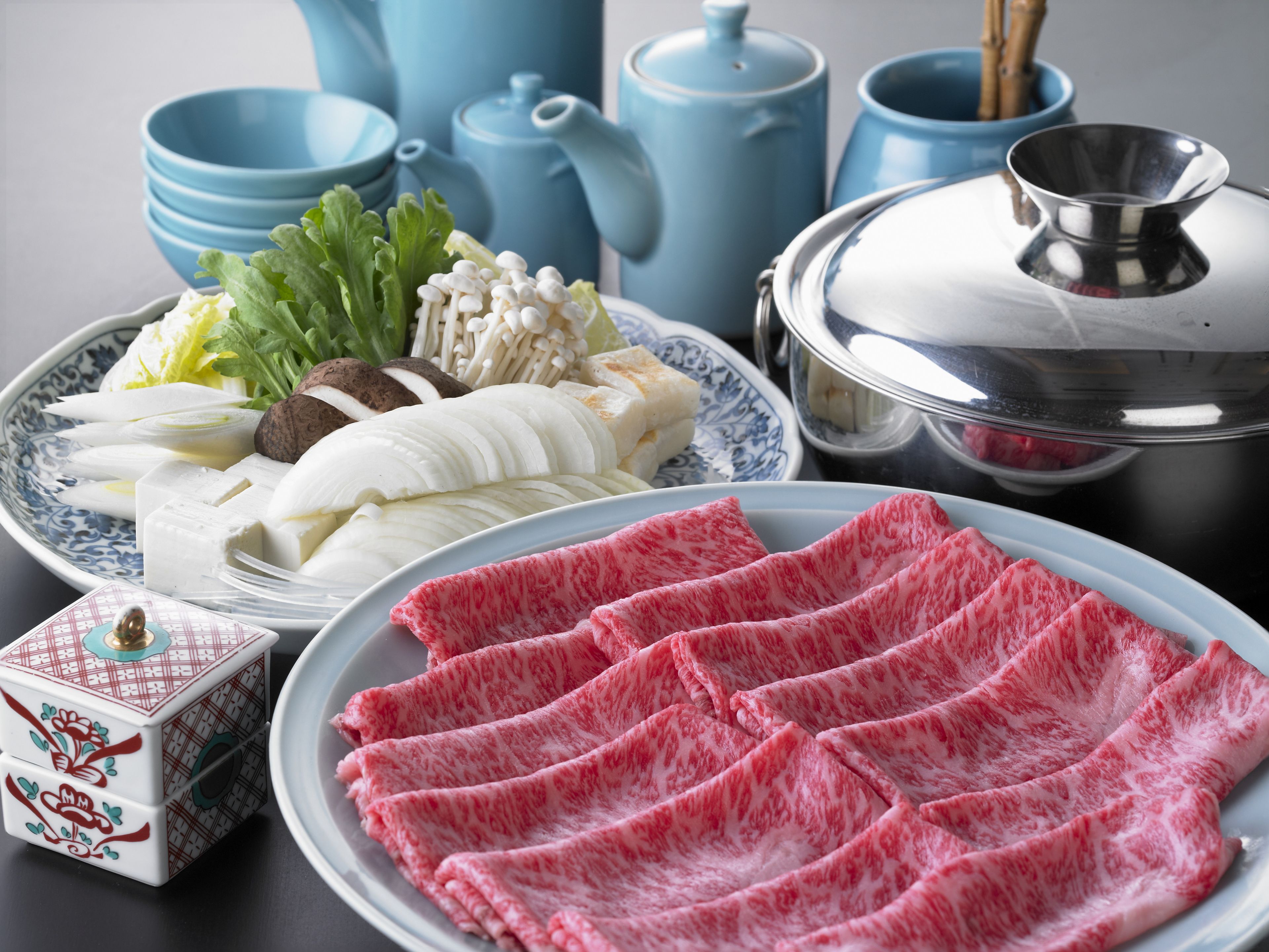 A table with various food items, including sliced meat, vegetables, and a decorative box.