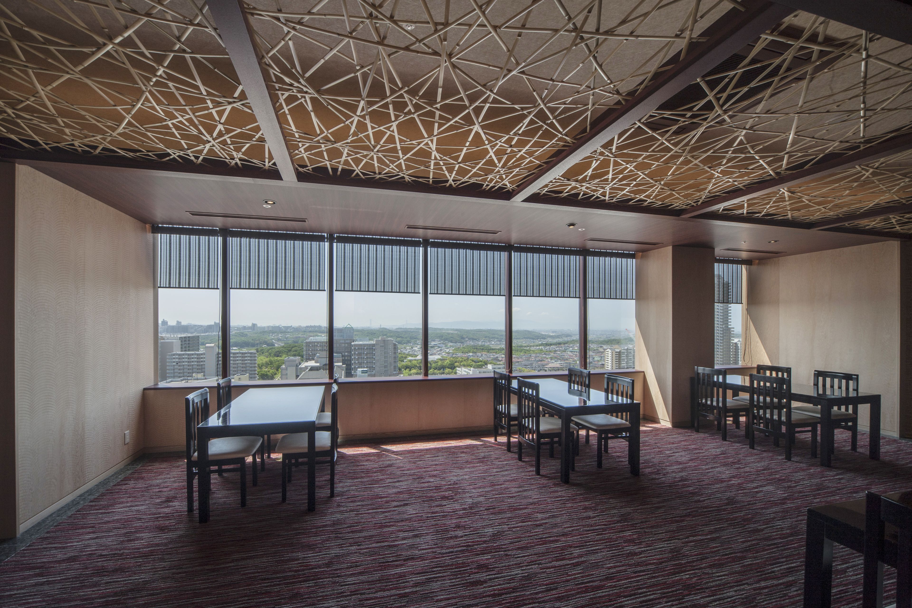 A conference room with a high ceiling, large windows, and a panoramic city view.