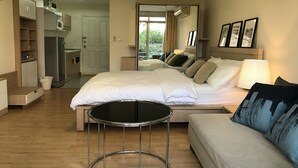 A hotel room with a bed, a sofa, a small table, a kitchenette, and a balcony view. - The Link Onnut by May (Bangkok)