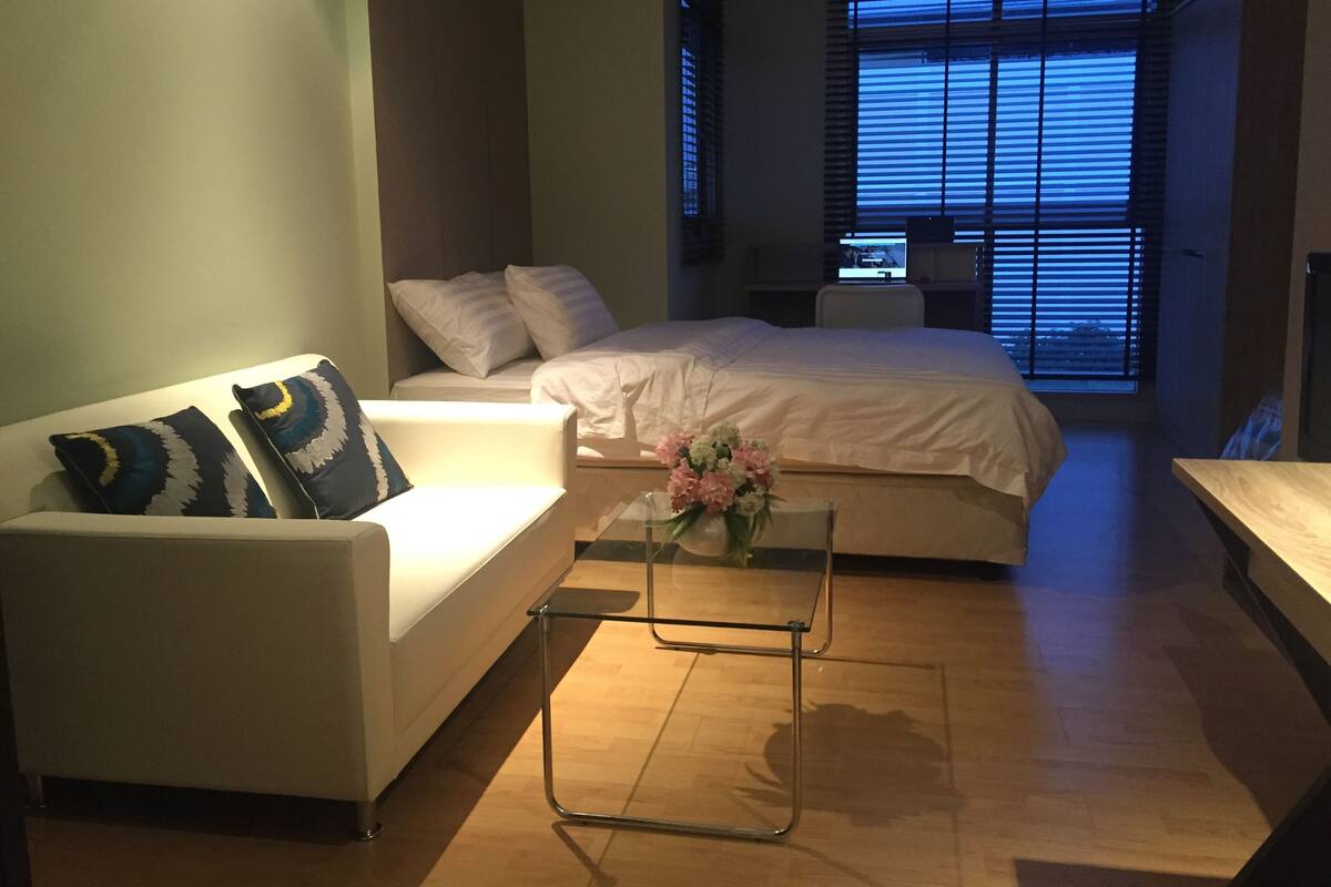 A modern bedroom with a bed, a sofa, and a glass coffee table.