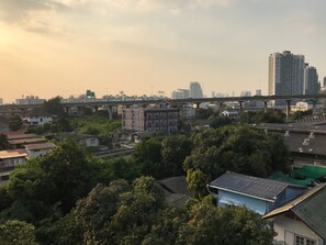 A cityscape with a mix of residential and commercial buildings, a bridge, and a high-rise building in the background. - The Link Onnut by May (Bangkok)