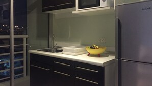 A modern kitchen with a stainless steel refrigerator, a microwave, and a sink. - The Link Onnut by May (Bangkok)
