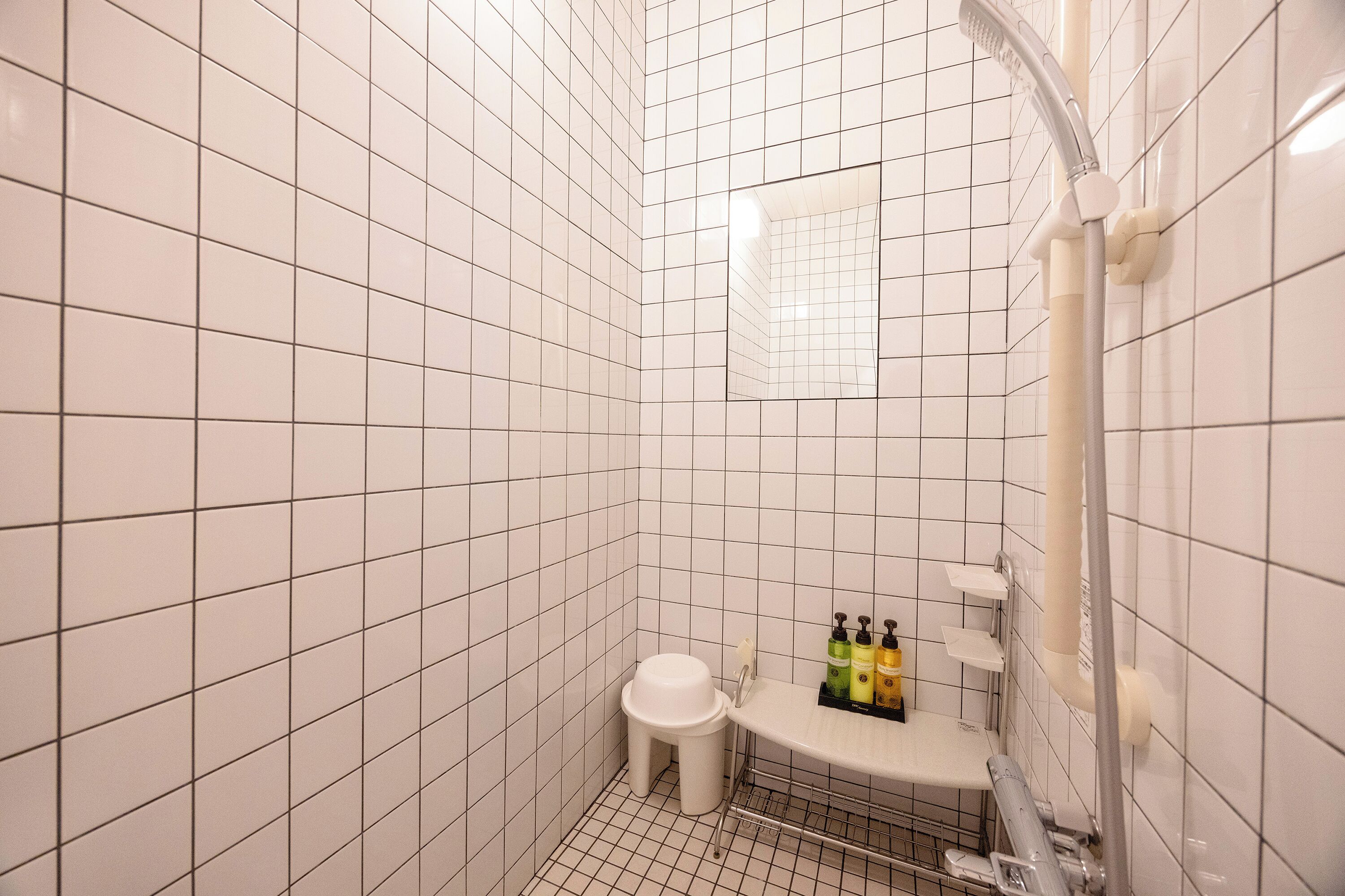 A small, tiled bathroom with a toilet, sink, and shower.
