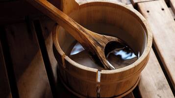 A wooden bucket with a wooden ladle inside, placed on a wooden bench.