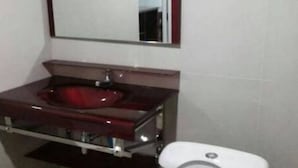 A bathroom with a marble sink, a mirror, and a white toilet.