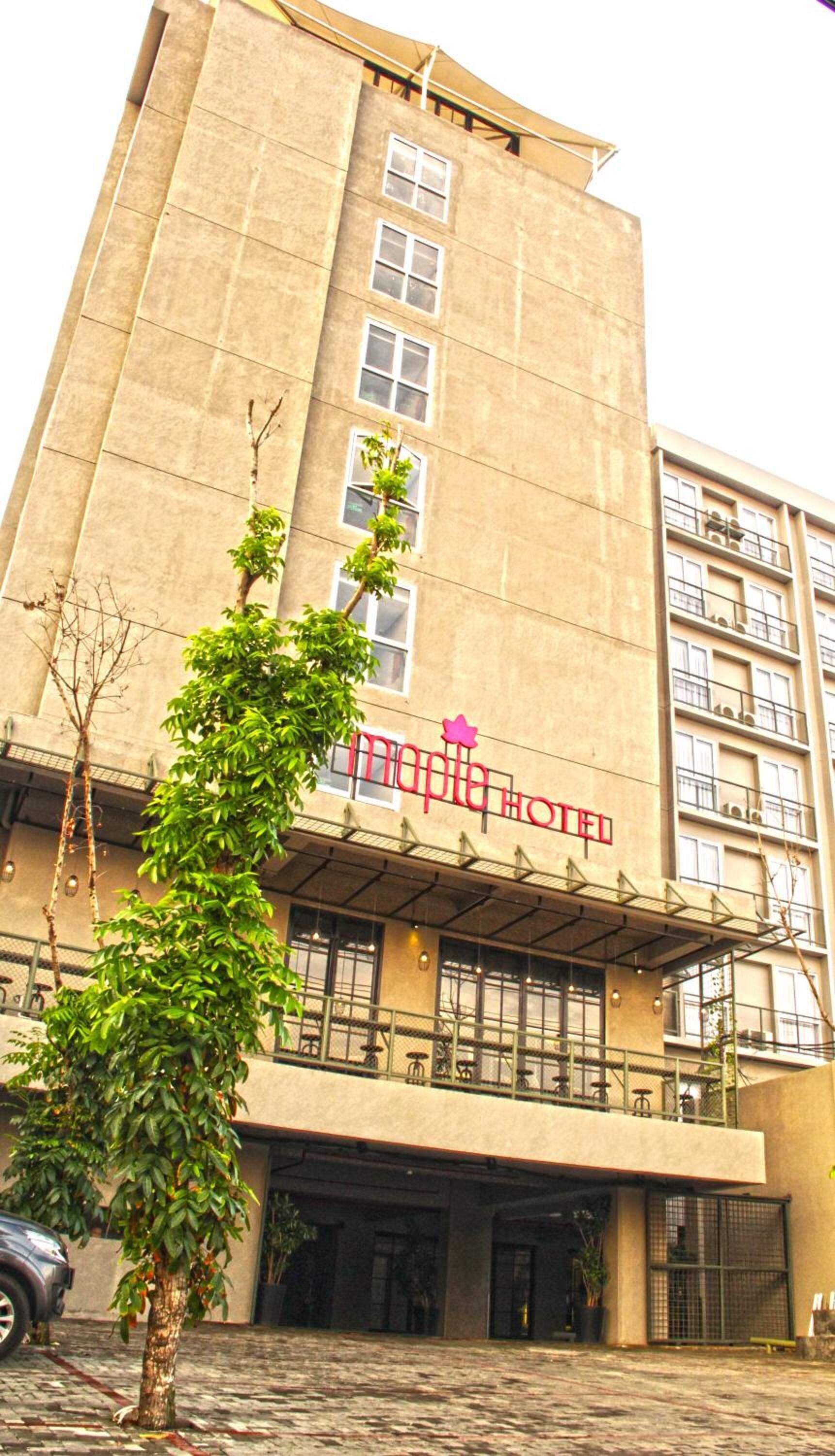A tall, beige building with a sign reading "Maple Hotel."