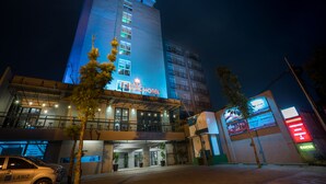 Un hotel con un letrero llamativo, varios pisos y una entrada bien iluminada.