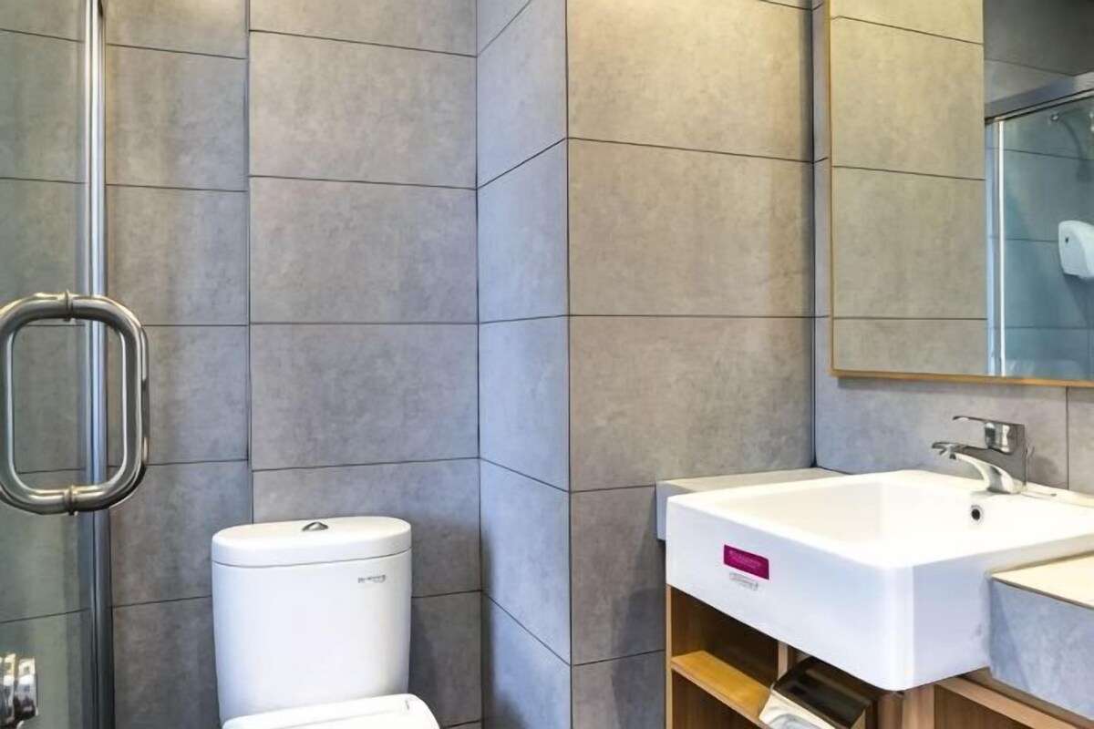 A bathroom with a toilet, sink, and mirror.