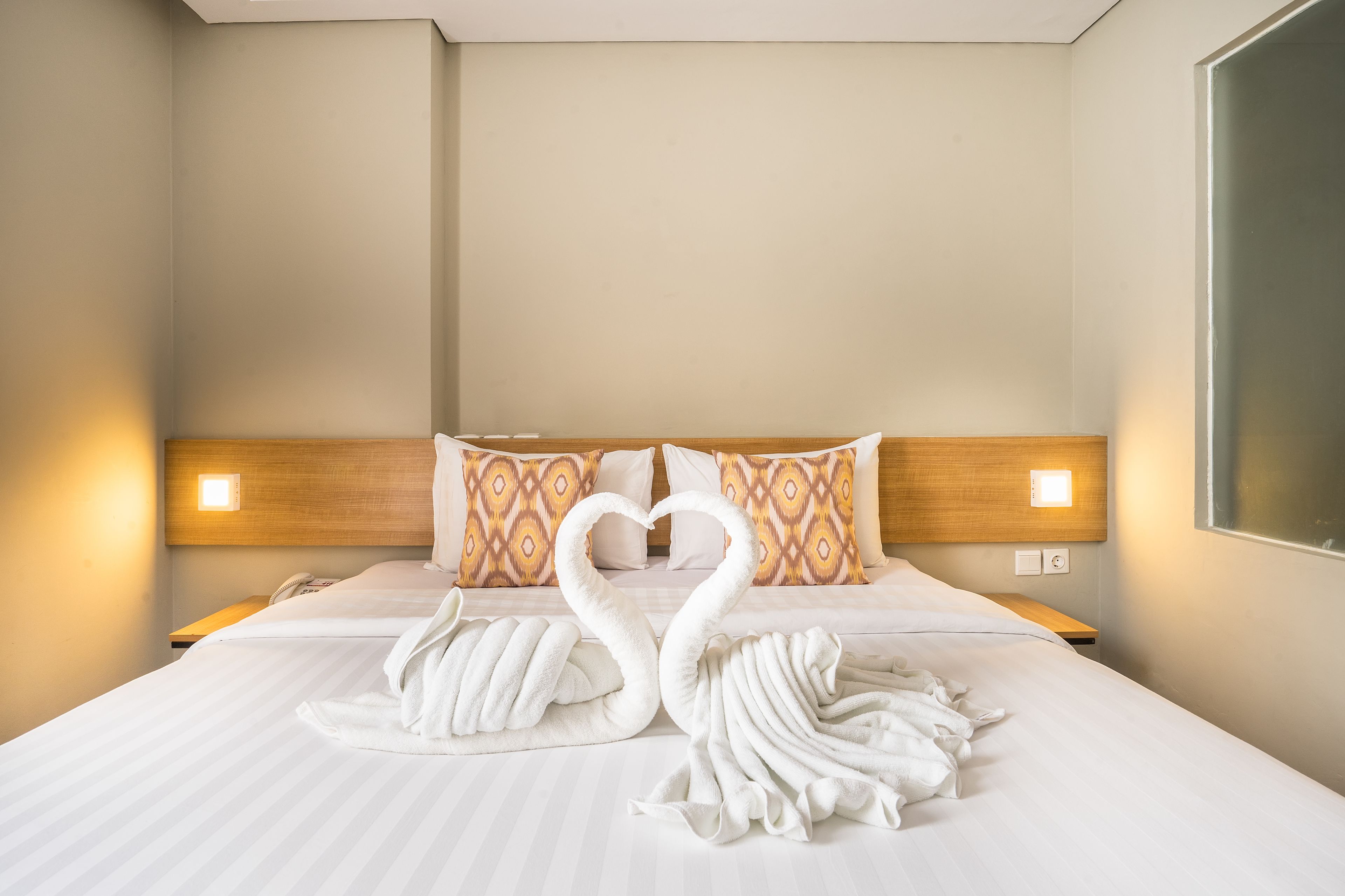 Une chambre d’hôtel avec un lit, deux lampes fixées au mur et une grande fenêtre.