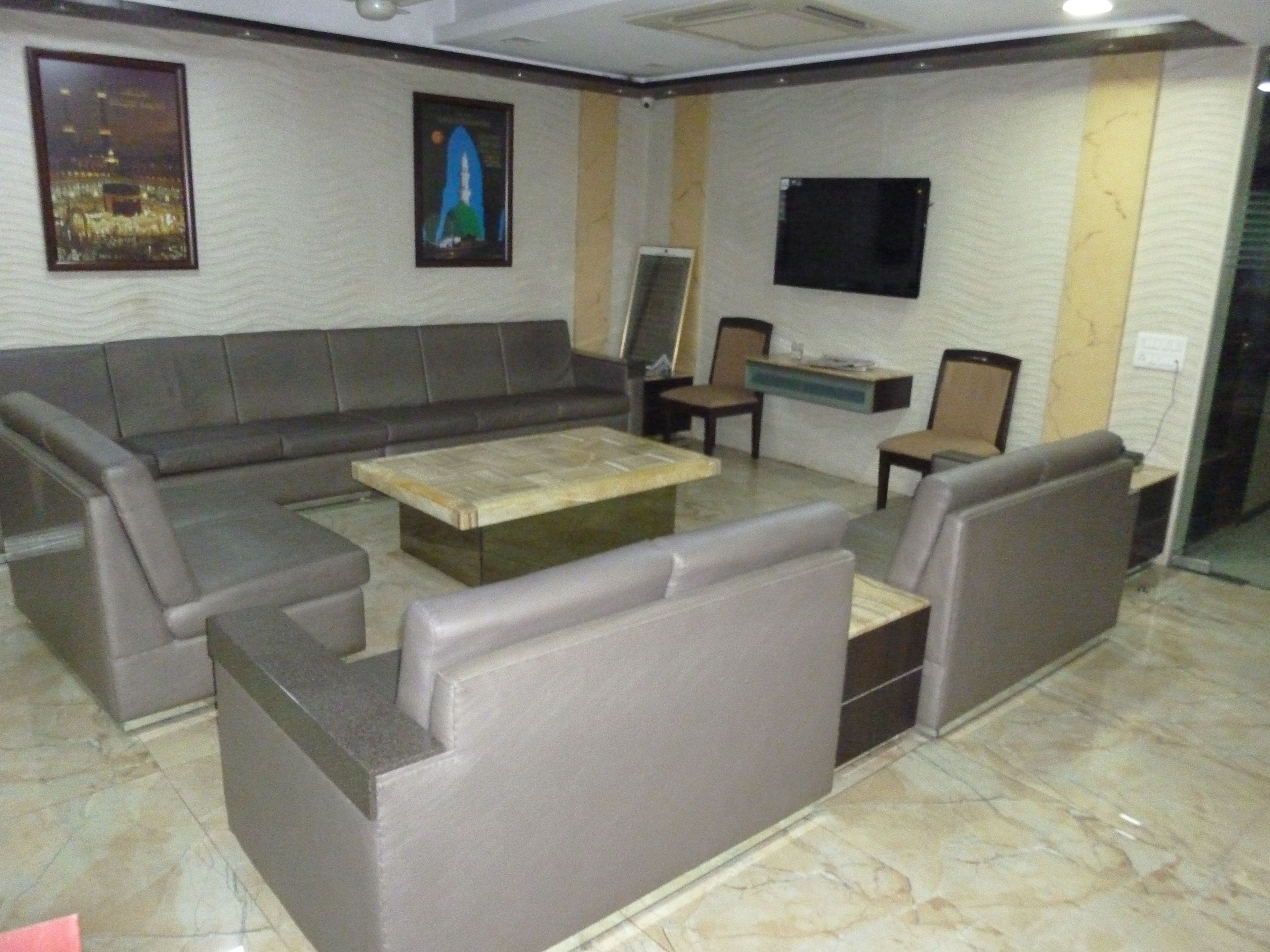 A modern living room with a sectional sofa, a coffee table, and a flat-screen TV mounted on the wall.