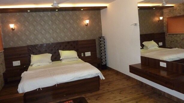 Een moderne hotelkamer met een groot bed, houten hoofdbord en in het plafond geïntegreerde verlichting.