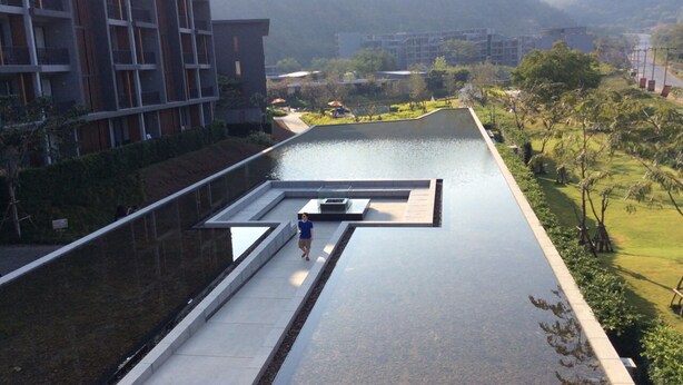 Eine Dachterrasse mit Pool, umgeben von Grünflächen und modernen Gebäuden.