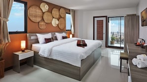 Habitación de hotel moderna con una cama grande, mesitas de noche, vistas al balcón y un paisaje urbano visible a través de la ventana.