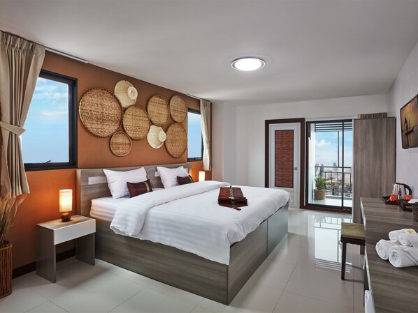 A modern hotel room with a large bed, bedside tables, a view through the balcony, and a cityscape visible through the window. - Baan Thai Boutique (Bangkok)