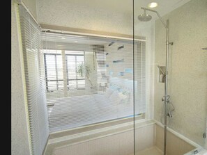A bathroom with a glass shower enclosure, a bathtub, and a window with blinds. - Away Baan Nub Kluen Beachfront at HuaHin (Hua Hin)