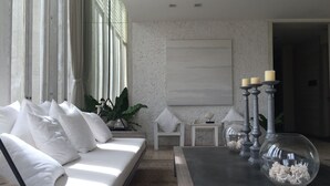 A modern living room with a white sofa, a glass coffee table with decorative items, and a large abstract painting on the wall. - Away Baan Nub Kluen Beachfront at HuaHin (Hua Hin)