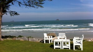 A beach with white chairs and tables, a large tree, and the ocean. - Away Baan Nub Kluen Beachfront at HuaHin (Hua Hin)