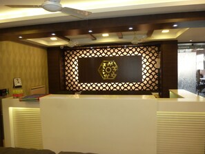 A reception area with a modern design, featuring a decorative panel with geometric patterns and a central emblem. - Hotel Orient Palace (Mumbai)