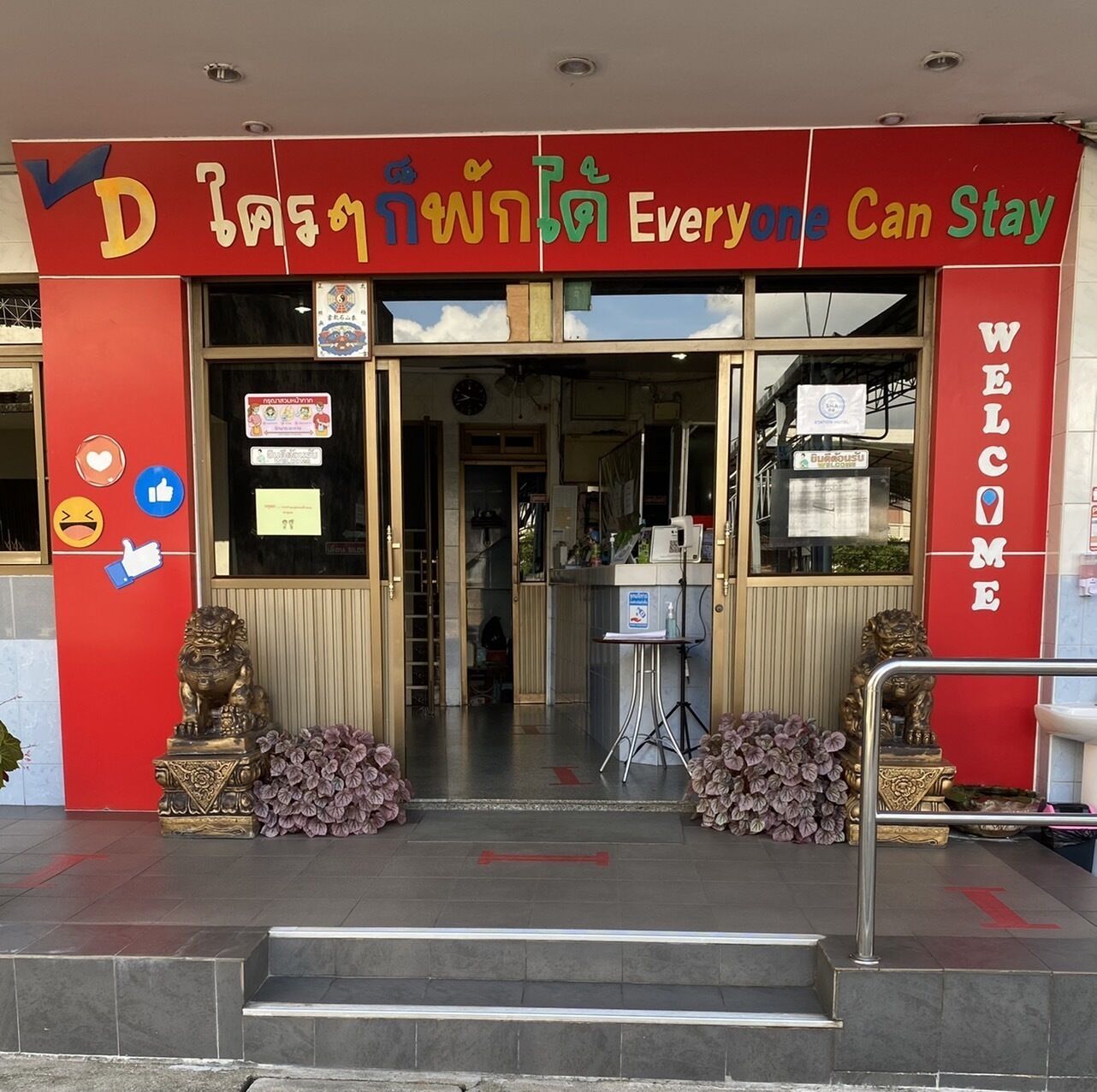 A red building with a sign reading "Everyone Can Stay" and a "WELCOME" sign on the right.