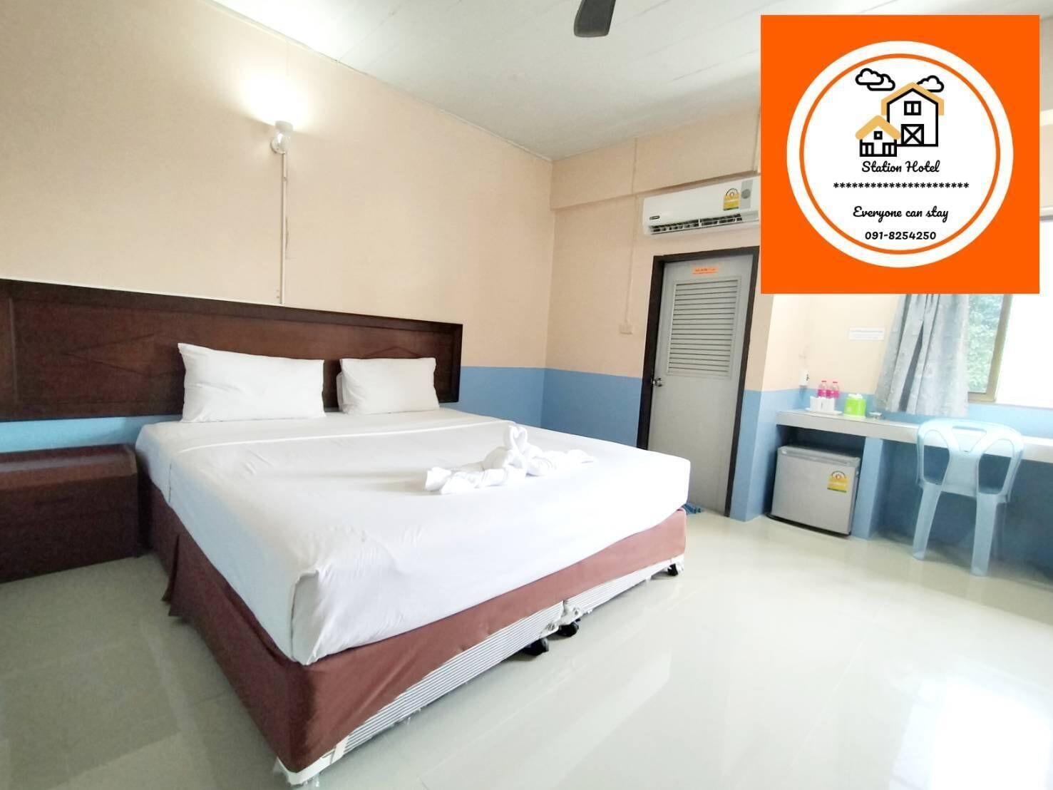 A hotel room with a bed, bedside table, and a desk with a chair.