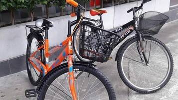 Una bicicleta con canasta y asiento, estacionada sobre una superficie de concreto.