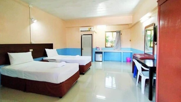 Habitación de hotel con dos camas, un escritorio, una silla, una mesita y una ventana.
