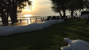 A beachside area with lounge chairs and a turtle sculpture. - Away Las Tortugas Beachfront (Hua Hin)