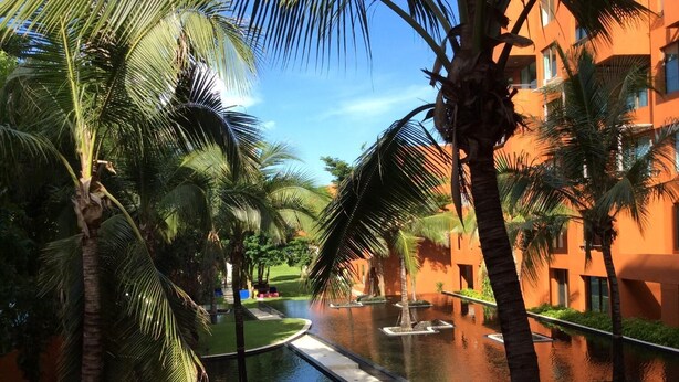 A water canal with palm trees and a building with orange walls. - Away Las Tortugas Beachfront (Hua Hin)
