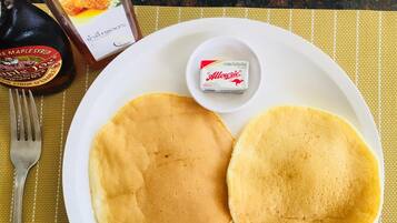 Un plato con dos tortitas y un recipiente pequeño de crema 'Allourie' sobre un mantel individual amarillo.