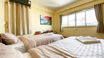 Habitación de hotel con dos camas, un cuadro en la pared y una ventana con cortinas.