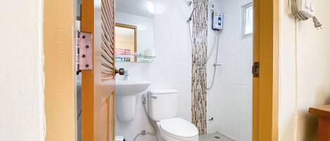 A bathroom with a toilet, sink, and shower.