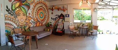 A cozy cafe with a mural, a sofa, tables, and chairs.