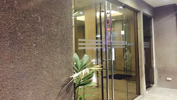 Entrada de un edificio con puerta de cristal, planta en maceta y suelo de baldosas.