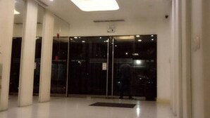 Un vestíbulo espacioso con un diseño moderno en el techo, puerta de entrada de vidrio y un piso limpio y reflectante.