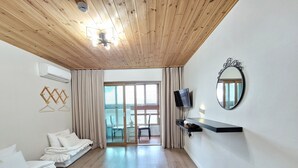 A modern hotel room with a wooden ceiling, a sliding glass door to a balcony, a flat-screen TV, and a mirror on the wall. - Starlightdrops Pension (Jeju City)