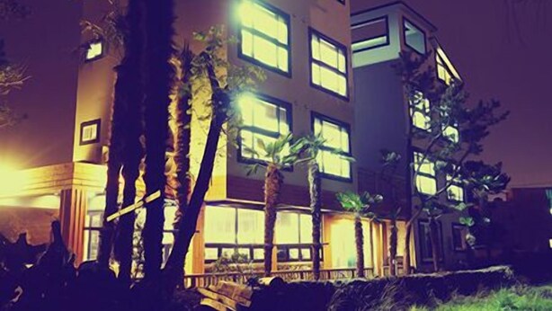 A multi-story hotel with illuminated windows and a modern architectural design. - Starlightdrops Pension (Jeju City)